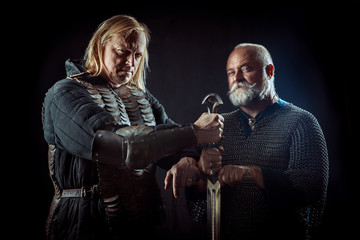 Two powerful knights are holding one sword.