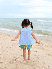 Cute child girl playing sand at the beach