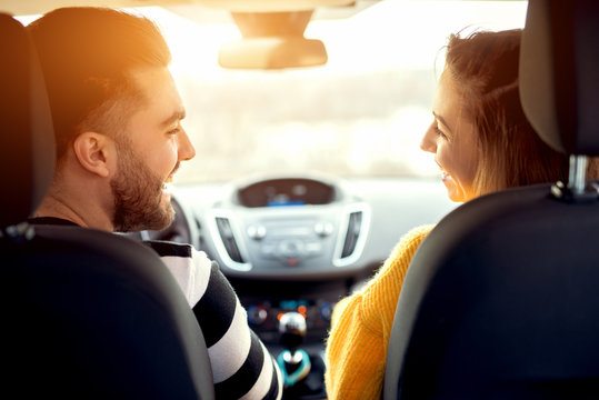 Back view of happy couple enjoying car ride, smiling cheerfully.