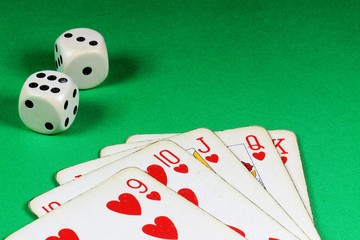 Poker cards and bone dice on green background.