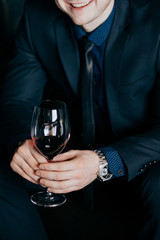 successful man keeps watch and clothes With a glass of red wine