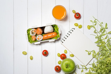 Bento box with different food, fresh veggies and fruits. Notebook with copyspace.