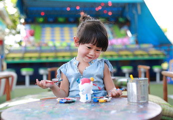 Child painting, little girl having fun to paint on stucco doll