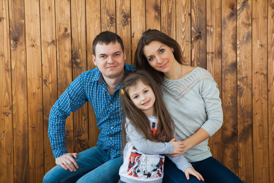 Haapy young family on wooden background in casual clothing.