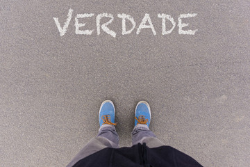 Verdade, Portuguese text for Truth text on asphalt ground, feet and shoes on floor