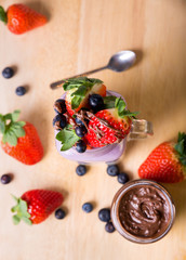 yogurt with fruits strawberry and blueberries in a glass on wooden background