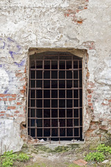 Fototapeta na wymiar abandoned grunge cracked brick stucco wall with a window grilles