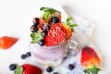 chocolate topping on strawberries and blueberries fruits with yogurt protein in a glas