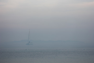 Blurred sailboat in the fog-covered sea. 