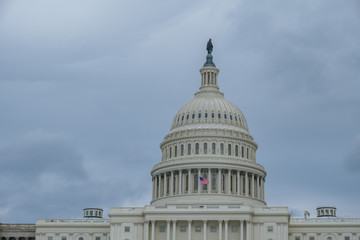Fototapeta na wymiar U.S. Capitol Dome and Flag on a Cloudy Day