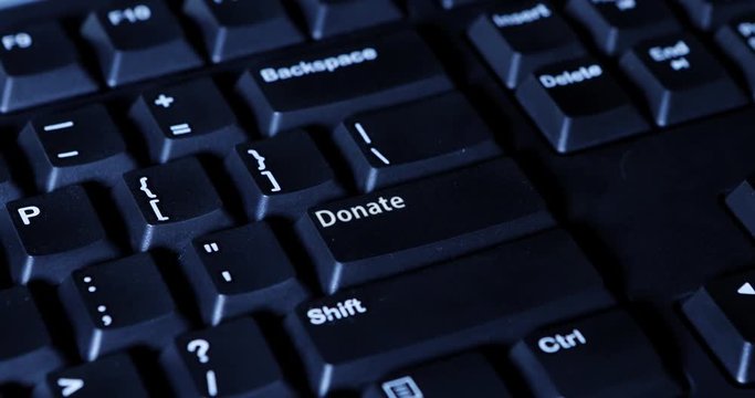 Macro video footage of a male hand pressing a Donate button on the computer keyboard