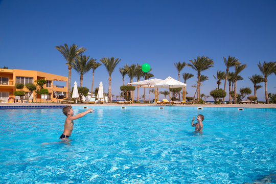 Two kids playing with ball in the pool
