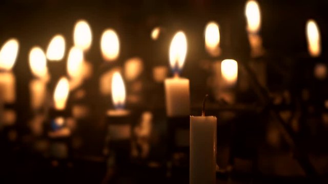 Video footage of hand burns a candle in the church at night with a candle light
