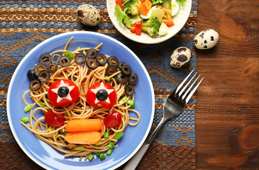 Plate with creative pasta for children on wooden background