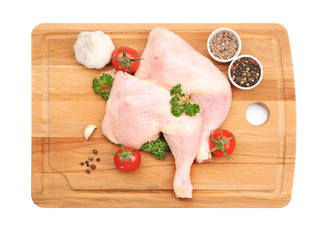 Wooden board with raw chicken thighs on white background