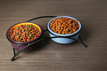 Cat food in bowls on wooden background