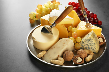 Tray with variety of cheese and nuts on grey background
