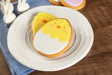 Plate with Easter sugar cookies on wooden background