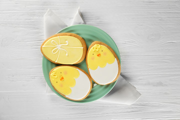 Plate with Easter sugar cookies on wooden background