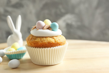 Easter cupcake near white rabbit on wooden table