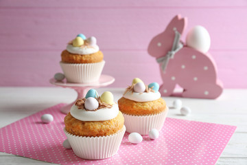 Delicious Easter cupcakes on white table against pink background
