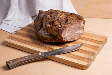 Baked ham with herbs and spice on wooden board.