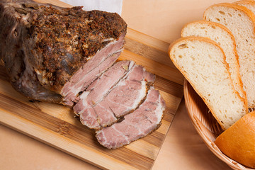 Baked pork with herbs and spice on wooden board and and slices white wheat bread.