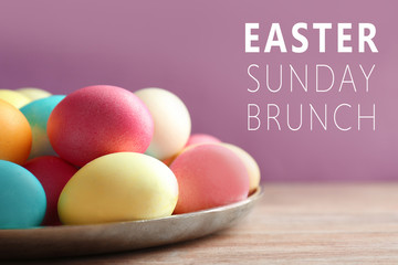 Metal dish with colorful Easter eggs on wooden table, closeup