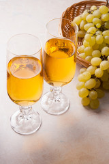 White wine and grapes. White wine in glasses and grapes on light marble background.