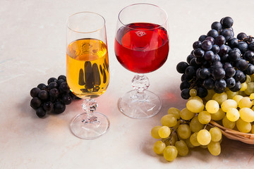 Wine and grapes. White and red wine in glasses on light marble background.