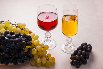 Wine and grapes. White and red wine in glasses on light marble background.