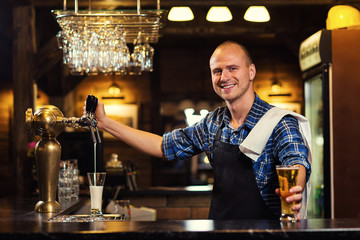 Bartender pouring the fresh beer in pub,barman hand at beer tap pouring a draught lager beer,beer from the tap,Filling glass with beer,fresh beer,pub.Bar.Restaurant.European bar.American bar.