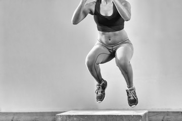 black woman is performing box jumps at gym