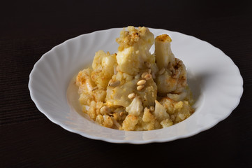 Baked cauliflower with roasted pine nuts on a plate