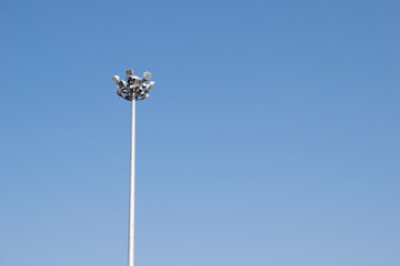 Lonely stadium light or lamp post with Union of light bulb standing alone with clould and blue sky.