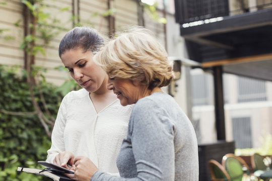 Businesswomen using digital tablet together at office yard