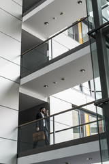 Businessman walking in office building, while using smart phone