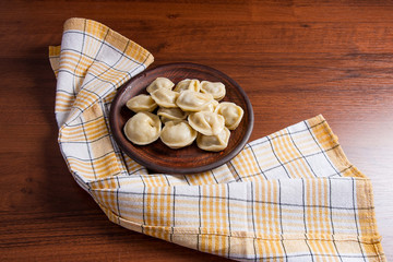 Boiled Ukrainian meat dumplings or ravioli on wooden background.