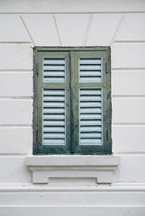 Old green wood window and white wall of building.