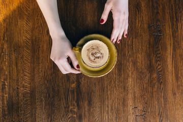 girl's hands holding coffee cup. flat lay, top view