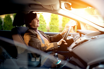 Middle aged woman looking forward driving a car.