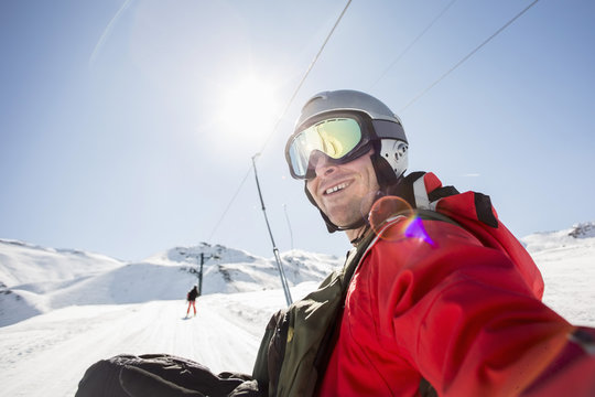 Smiling man in ski-wear on snow covered field against clear sky