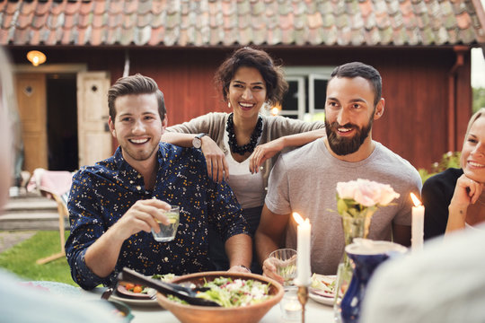 Smiling woman standing with friends at table in garden party