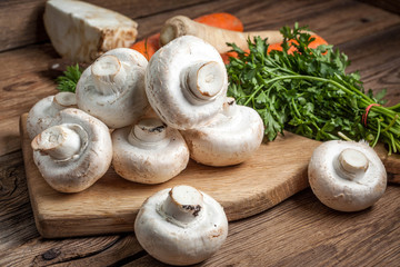Champignon mushrooms on a wooden cutting board.