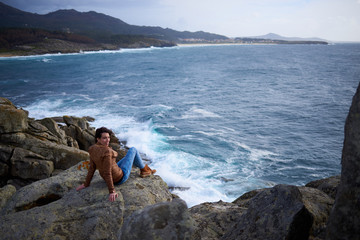 Mujer joven sentada en una roca en las ruinas del Castro de Baroña