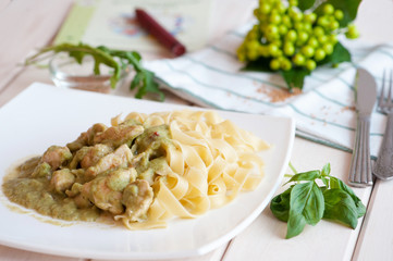 Fettuccine and chicken with fresh basil and pesto in a white plate