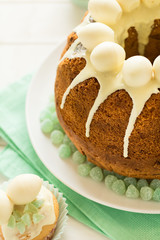Glazed Easter cake decorated candy eggs on white wooden table. Selective focus
