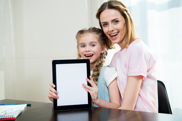 Happy mother and daughter showing digital tablet at home