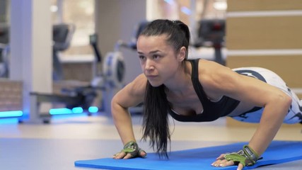 Fitness young woman doing push ups on exercise mat. Healthy young female working out at home.