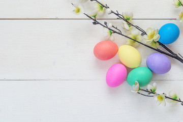 Easter eggs and apple tree branch on white wooden background. Space for text.